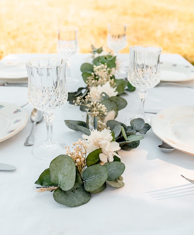 Un chemin de table en fleurs séchées rosa cadaqués disposé au centre d'une table dressée