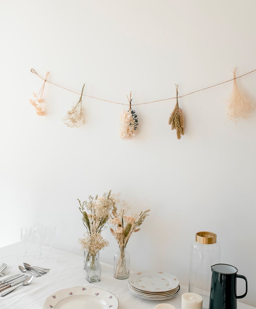 Guirlande en fleurs séchées disposée contre un mur