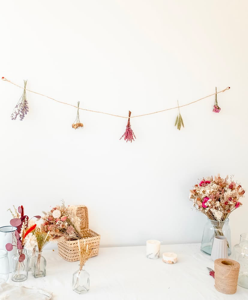 Guirlande en fleurs séchées disposée contre un mur