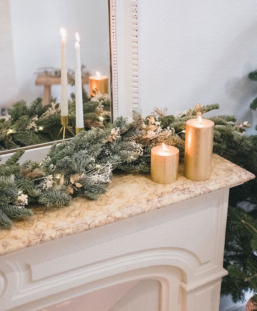 Guirlande de fleurs séchées sapin posée sur une cheminée surmontée d'un miroir ambiance tamisée