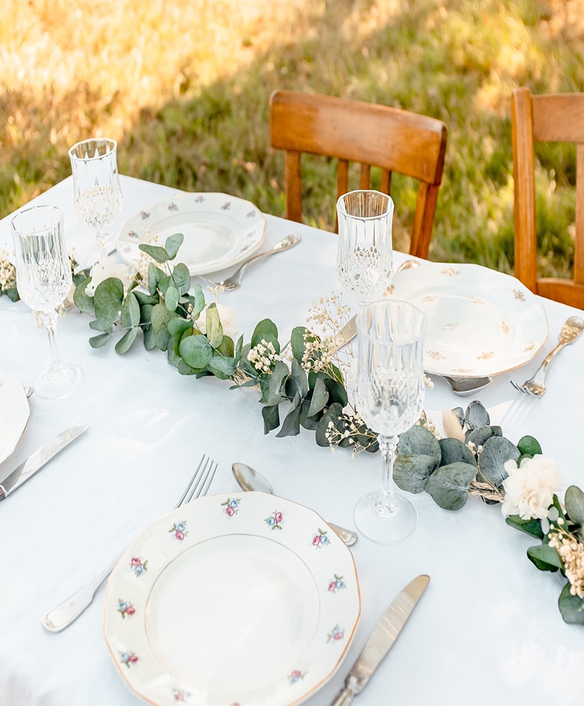 Un chemin de table en fleurs séchées rosa cadaqués disposé au centre d'une table dressée