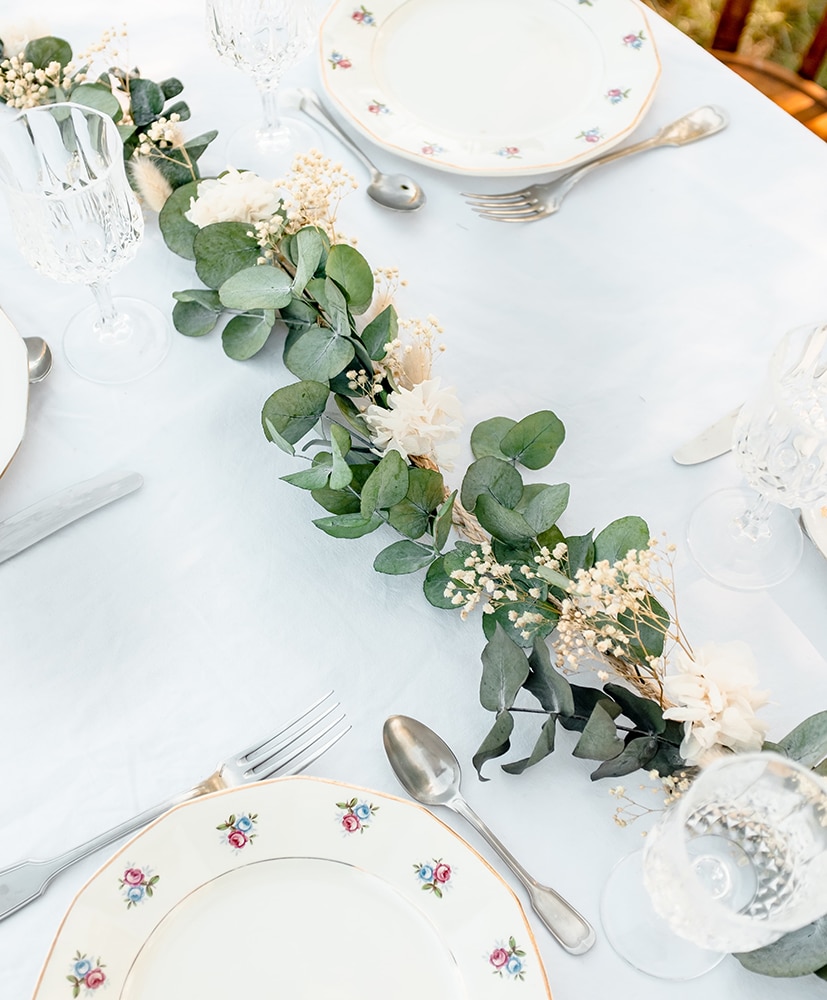 Un chemin de table en fleurs séchées rosa cadaqués disposé au centre d'une table dressée